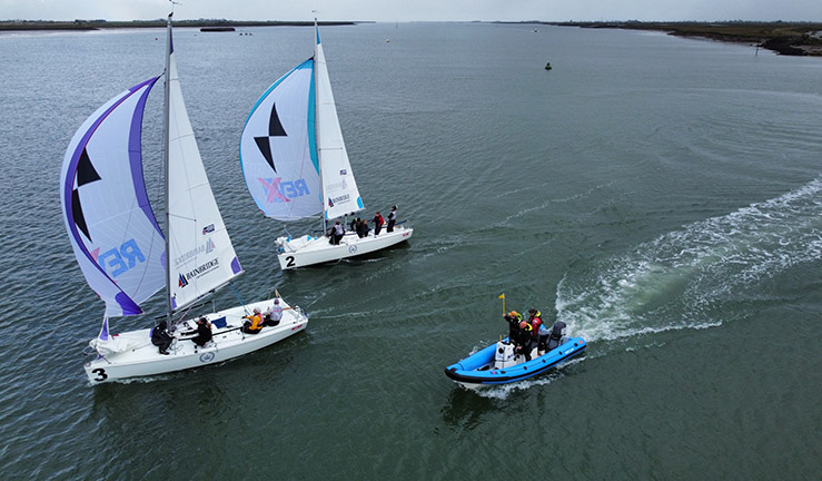 Two boats match racing on a downwind leg at Burnham with an umpire RIB alongside.
