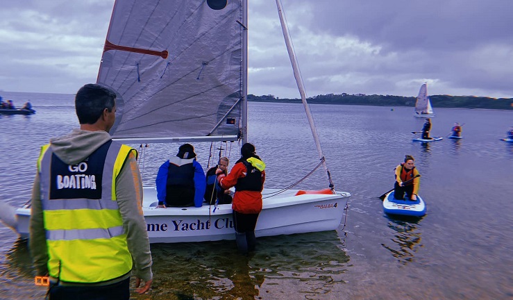 BYC Discover sailing day, people by the water with a sailing dinghy and SUP