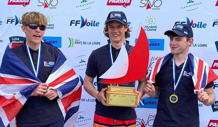 Ben Tylecote, Terry Hacker and Jamie Tylecote pictured with Union Jack flags and trophy after winning the Eurosaf Youth Match Racing European Championship 2023