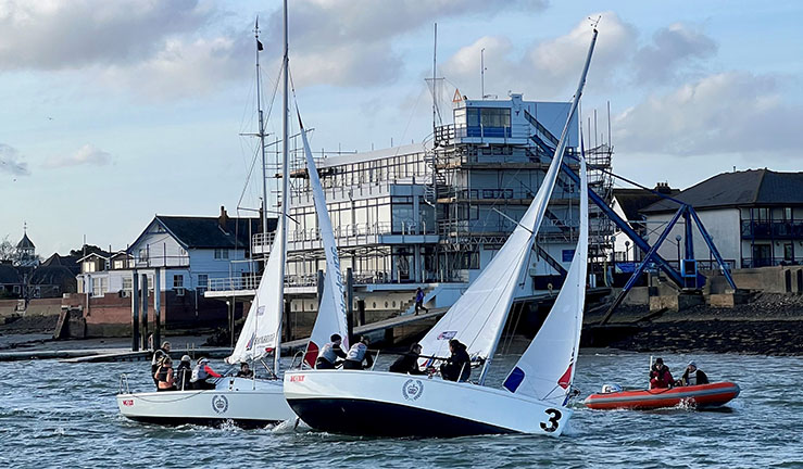 Two teams match racing in 707 keelboats with Royal Corinthian Yacht Club, Burnham on Crouch, in the background.