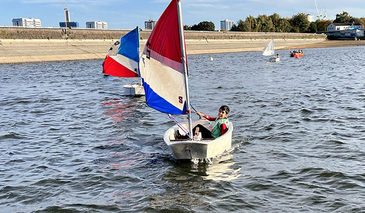 Young OnBoard sailor in an Optimist training boat on the water.