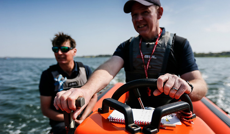 Powerboat driver and passenger on the water on a sunny day.