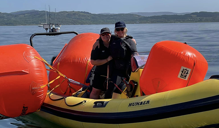 Women helping lay race buoys onboard inflatable power boats on a Scottish Loch in the sunshine. 