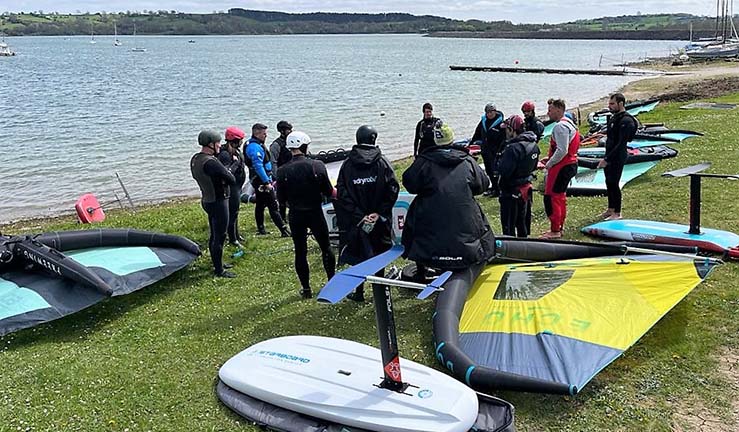 Group of participants on shore with winging equipment as part of instructor course.