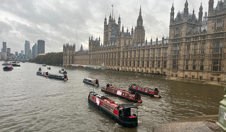 Several narrowboats are cruising past the Houses of Parliament