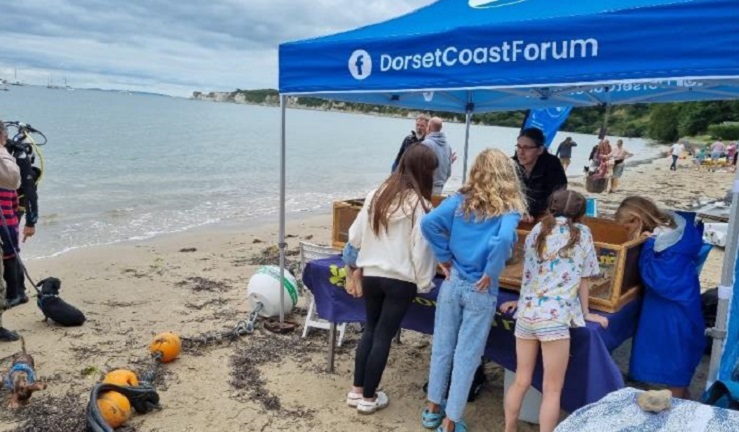 Three girls are talking to a member of the Dorset Coastal Forum.