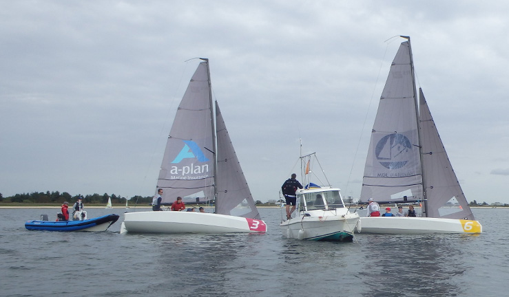 Two RS21 keelboats either side of a committee boat with a blue RIB to one side up on a grey day at the RYA Summer Match Racing Q2 event at Queen Mary SC, 2023.
