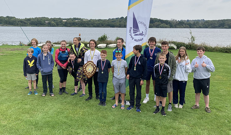 Group of 16 children with prizes on shore with lake in background after competing in a Derbyshire Youth Sailing event at Staunton Harold.