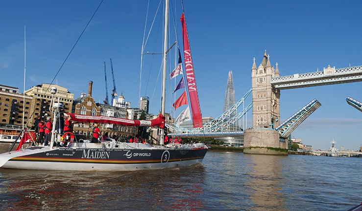 Maiden crew with Heather helming sail the yacht towards Tower Bridge in London on a sunny day with blue skies.