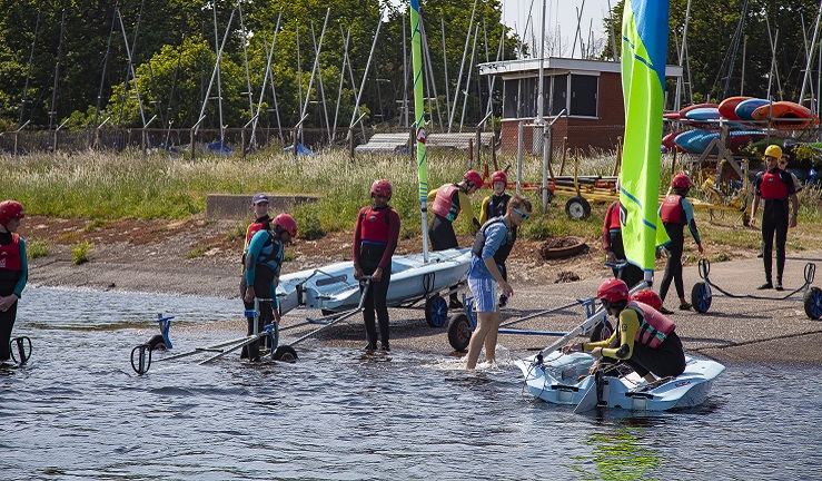 A group of people pulling dinghies out of the water at a club slipway