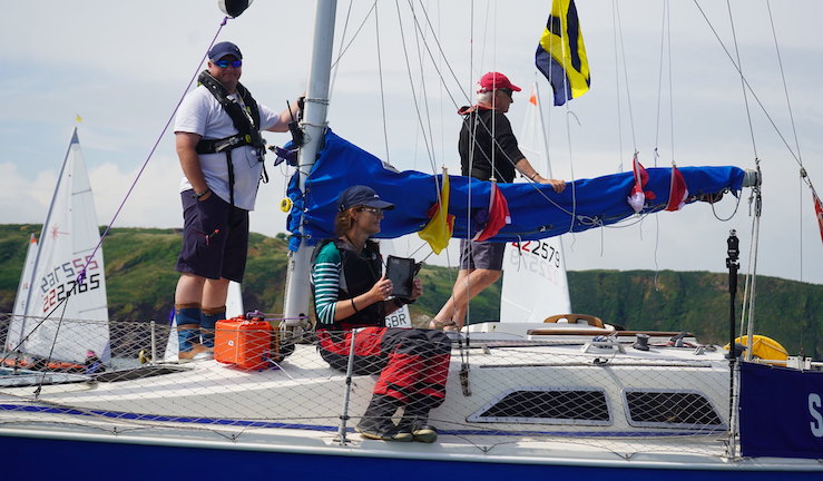 Group of people on a 'committee boat' running the racing at and event with ILCA dinghies in the background.