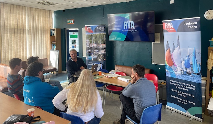Half a dozen people seated and gathered around a presentation at RYA North Regional Training Day at Derwent Reservoir SC.