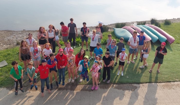 Group of around 40 on shore with lake in the background at a Dragon Series prizegiving.