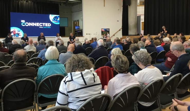 Rows of people seated and listening to the introductory session at the 2023 RYA Connected conference for the Midlands, with a screen at the front showing the title.