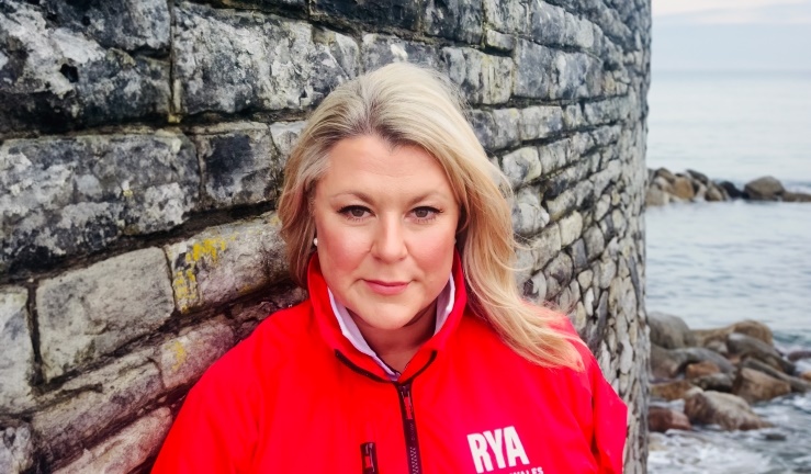 RYA Cymru Wales chair Sian Reynolds pictured in red branded jacket by harbour wall/sea.