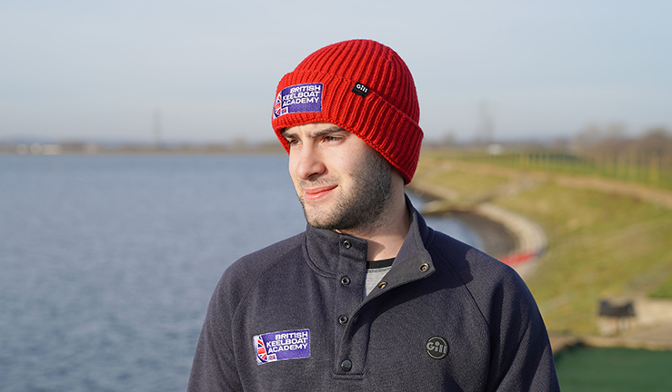 BKA recruit Ben Salva on shore in British Keelboat Academy branded blue sweatshirt and red hat.