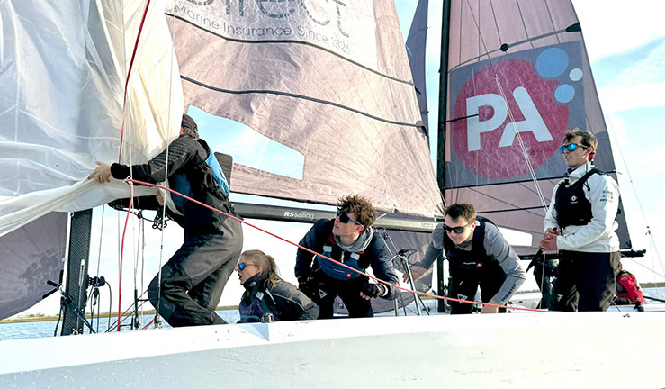 Team of five sailors working together to sail an RS21 keelboat.