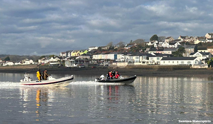 Two powerboats motoring along the shoreline in Swansea.