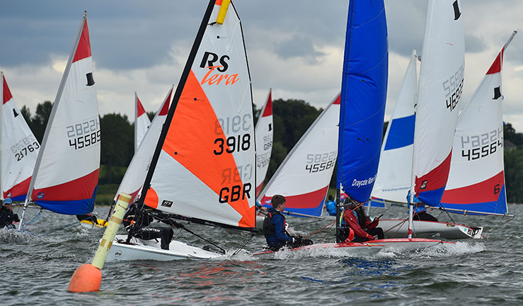 Junior dinghies with colourful sails racing at the NSSA Youth Regatta, Draycote Water, 2023.