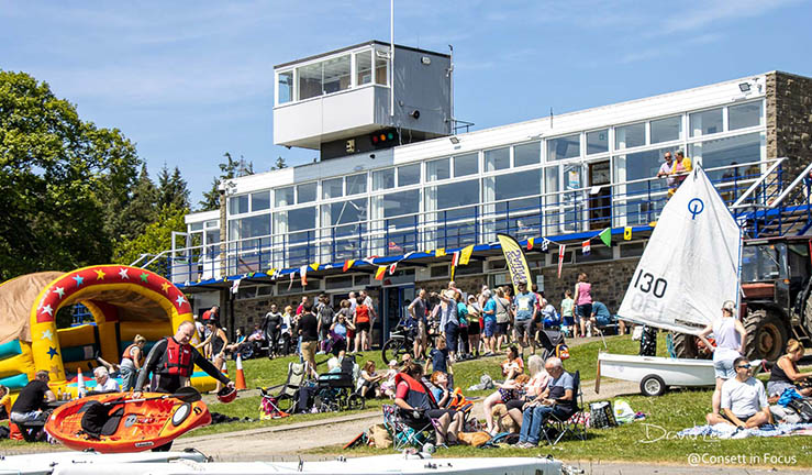 Lots of people having fun in the sun on shore in front of the clubhosue at Derwent Reservoir Sailing Club open day.