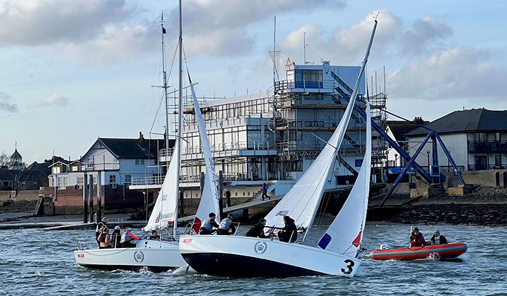 Two teams aboard 707 keelboats with a RIB sailing upwind in front of Royal Corinthian Yacht Club at Burnham on Cruoch.