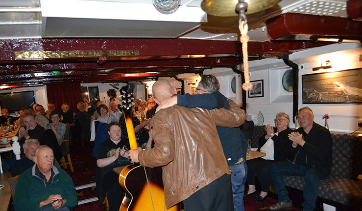 Musicians with guitar taking a bow to an audience aboard the Royal Northumberland YC lightship on a music night.