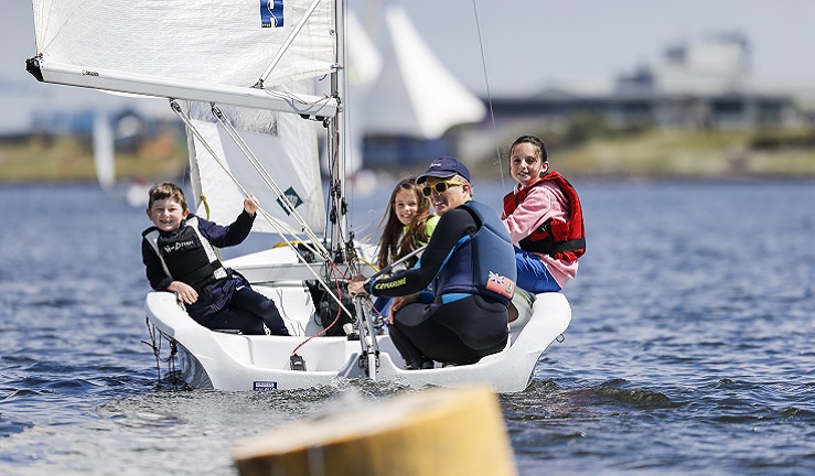 A group of people are sailing in a dinghy on a sunny day