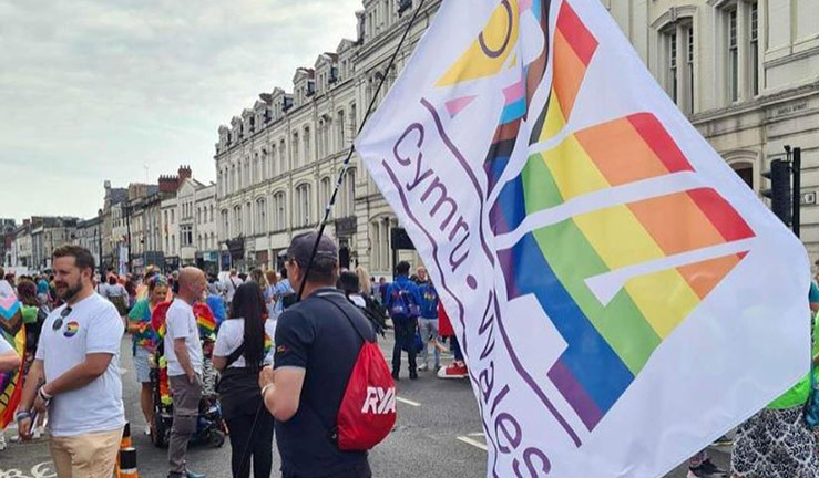 RYA Cymru Wales with multicoloured RYA pride flag walking with the crowds at Pride Cymru in Cardiff 2023.