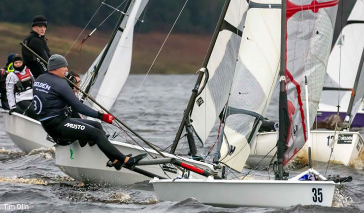 A skiff in the foreground - sailor out trapezing on the rack - racing with other boats in close quarters at the Yorkshire Dales SC Brass Monkey event 2023. 