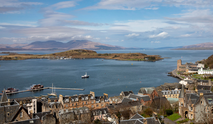 A wide view looking west over Oban Harbour with the islands in the distance and a Ferry making it's way out to the Firth of Lorne