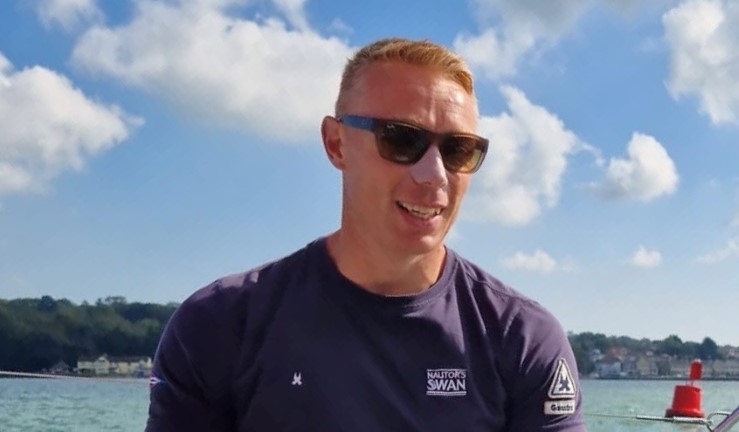 Headshot of Phil Devereux, new head coach for the British Keelboat Academy, water and blue sky with clouds background.
