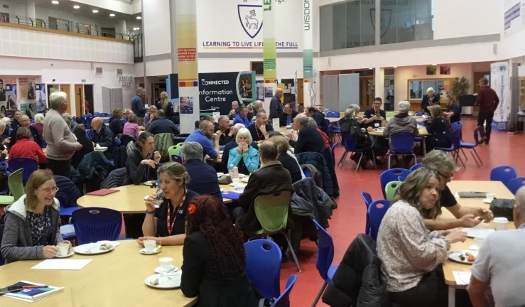 Lots of people sat around tables have a cuppa and a chat at the RYA Connected Conference for the Midlands 2024, Brockington College, Leicestershire.