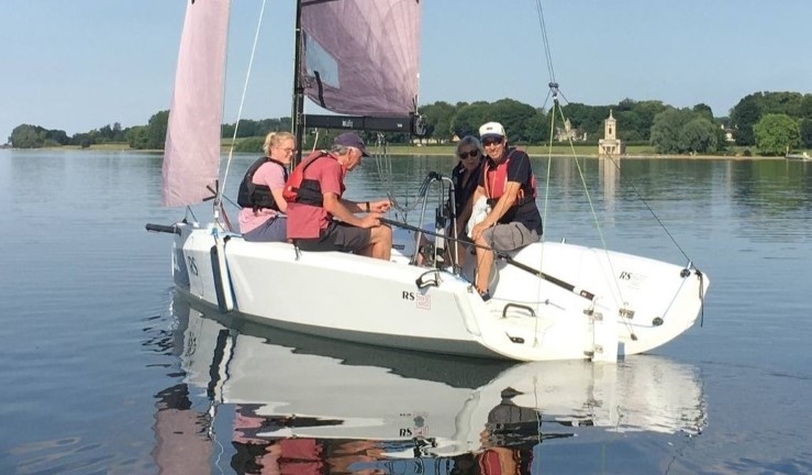 Four people in an RS21 having a gentle sail and a natter on a sunny calm day at Rutland Water following an RYA Midlands informal team gathering.