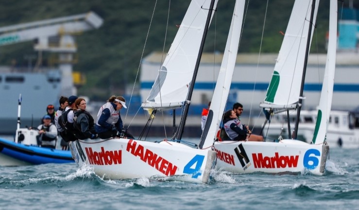 Two teams match racing upwind in Elliott 6m keelboats in Portland Harbour with blue RIB umpire boat behind.