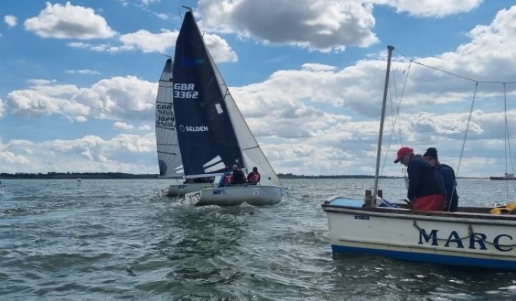 Three people at the back of the Marconi SC committee boat with SB20 keelboats on the Blackwater for Q4 of the 2024 British Keelboat League.