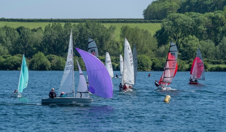 Good turnout of dinghies for racing at Notts County SC, May 2024, with two sail boat with purple spinnaker in the foreground heading towards a mark, sunshine and blue water!