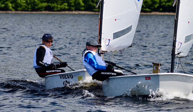 two young sailors competing in the RYA Scotland youth and junior championships each in their own white dinghy.