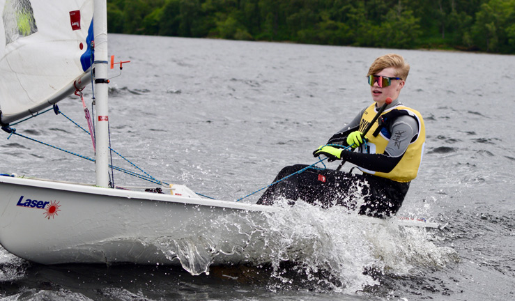 A young sailors competing in the RYA Scotland youth and junior championships in a white dinghy.