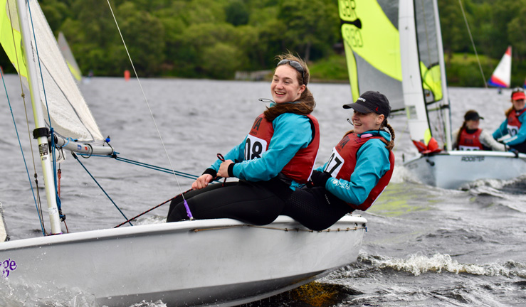 two young sailors competing in the RYA Scotland youth and junior championships in a white dinghy.