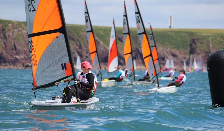 Fleet of RS Teras with orangse and white sails heading towards the camera and a windward mark at the Welsh Regional Junior Championships 2024.