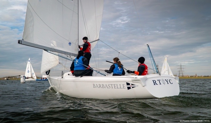 A school team in action putting on pole for spinnaker and sailing downwind in a Sonar keelboat at Q1 of the British Keelboat League 2024.
