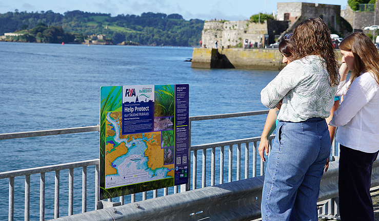 A group of people are reading an information board.
