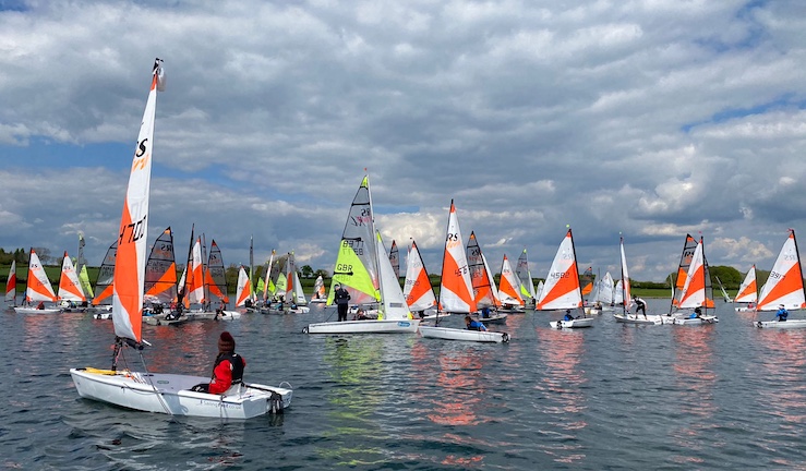 Fleet of RS Teras with white and orange sails with an RS Feva in the middle, on the water in sunshine with light winds and grey skies at the Eric Twiname Championships 20124.