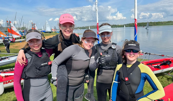 Group of five smiling junior sailors from Team Wales on shore  in the sunshine at Rutland SC for the Eric Twiname Champs 2024.
