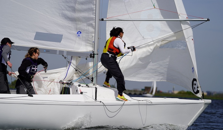 Three women sailing a keelboat and preparing pole for spinnaker.
