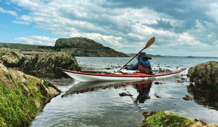 Canoeist paddling between rocks on the coast.
