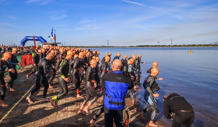 Swimmers taking part in a triathlon event about to jump into the water.