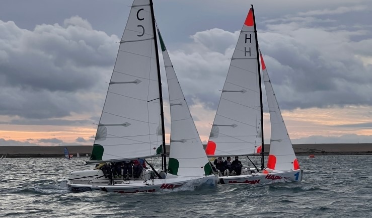 Two teams match racing in Elliott 6m keelboats in Portland Harbour as the sun goes down at WPNSA for the RYA Schools Match Racing Championship 2024.
