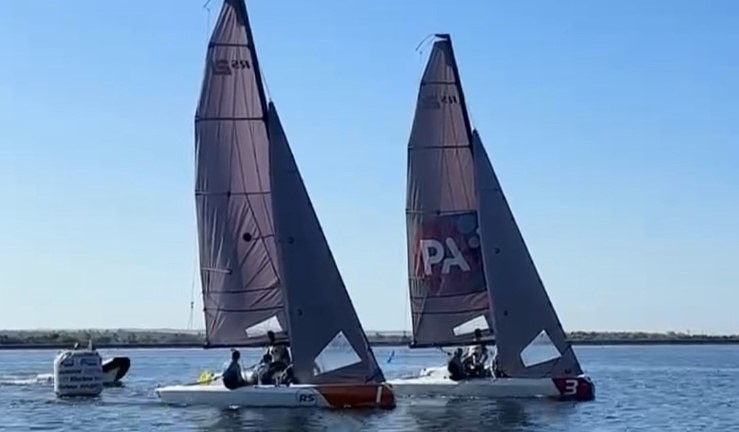 Two teams match racing RS21 keelboats upwind with with blue skies at Queen Mary SC, 2024 RYA Match Racing Series.