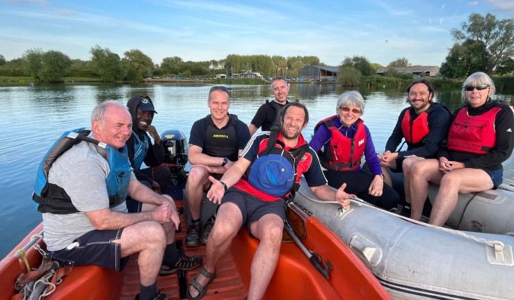 Regional manager Ben Hodgson with seven club members at Wanlip SC, all seated and smiling for the camera in two powerboats on the water by the shore.